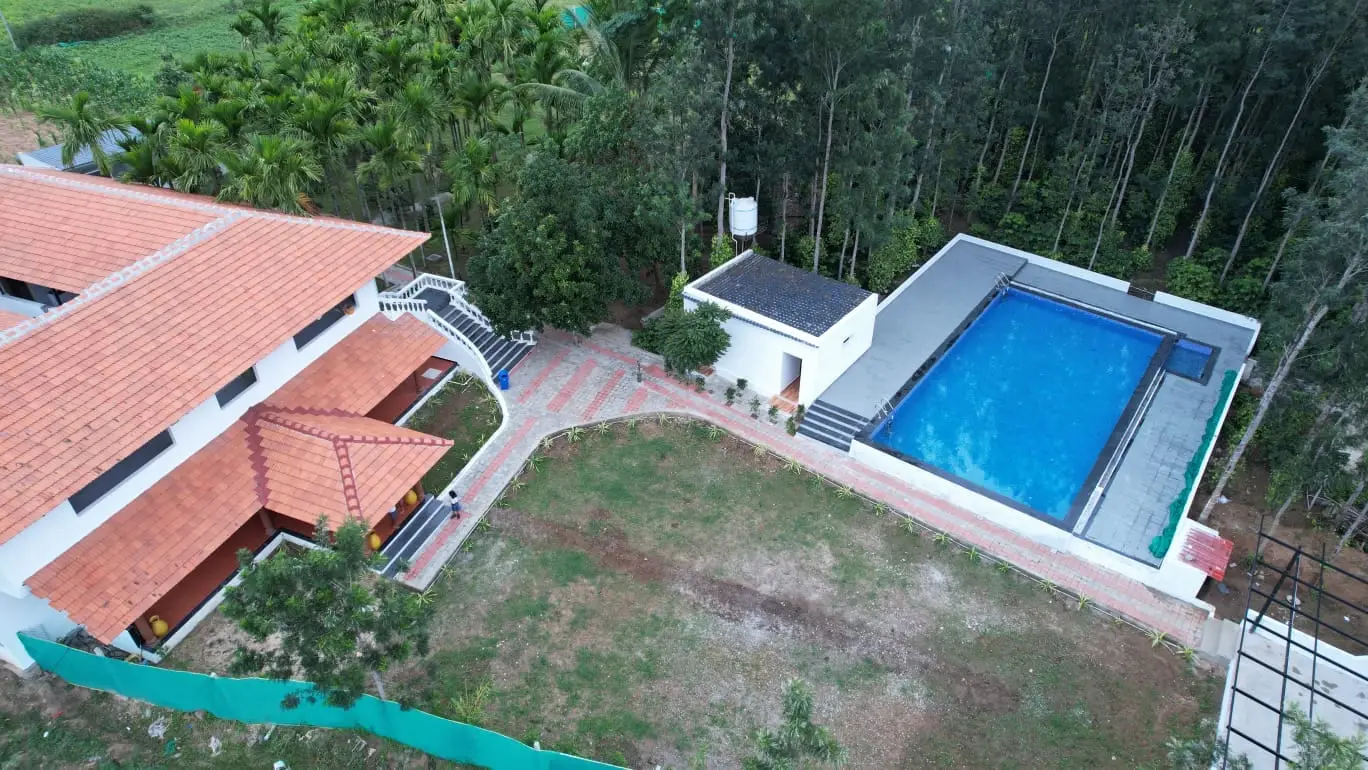 Aerial view of the retreat showing the tiled-roof villa, lawn and swimming pool surrounded by plantation