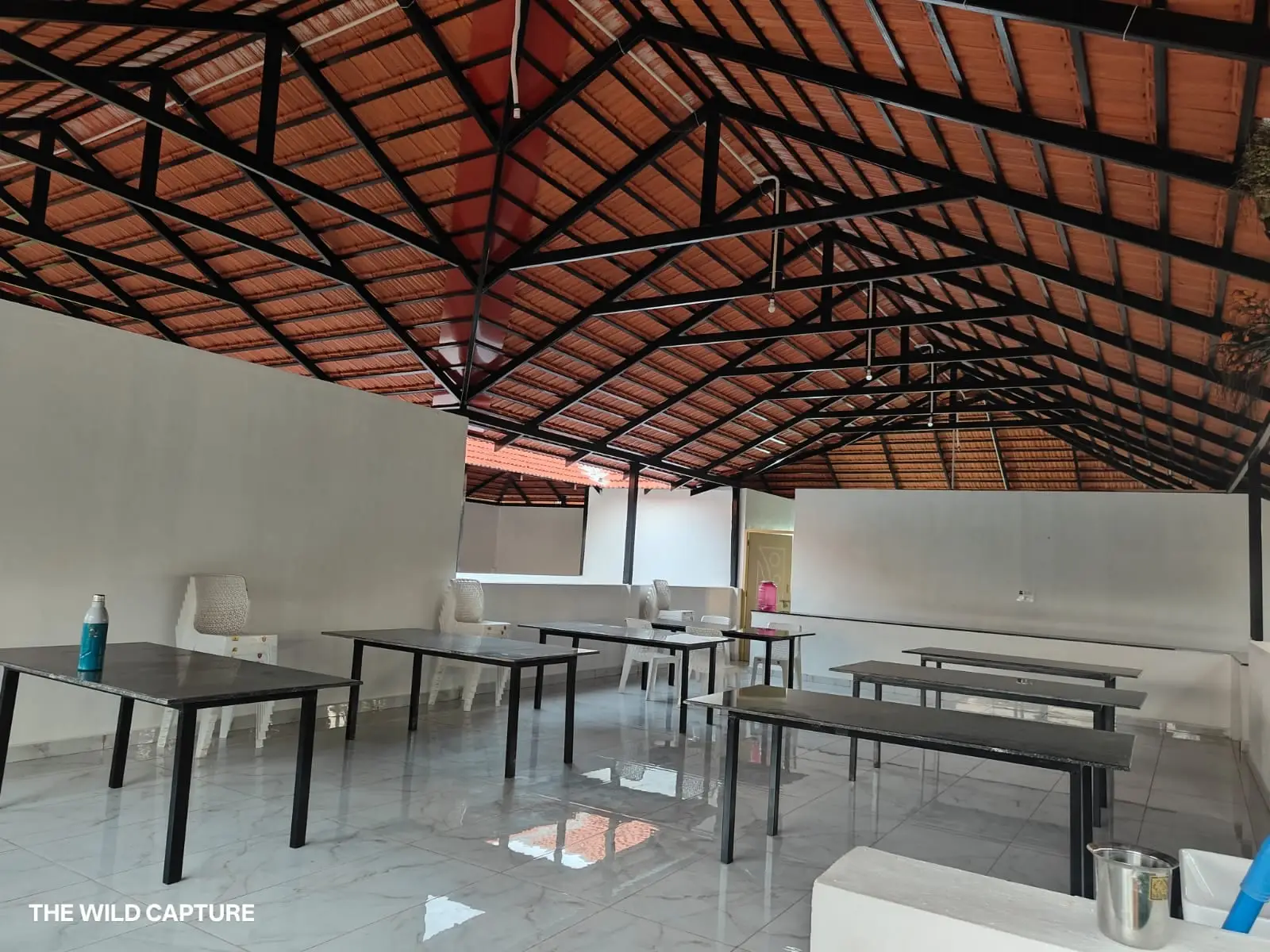 Open dining hall under an exposed truss and terracotta tile roof